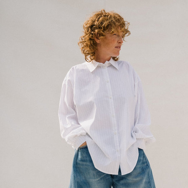 Person wearing a white shirt and blue denim shorts against a plain background