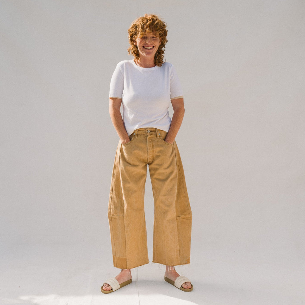 Person wearing a white t-shirt and beige wide-leg pants on a plain background