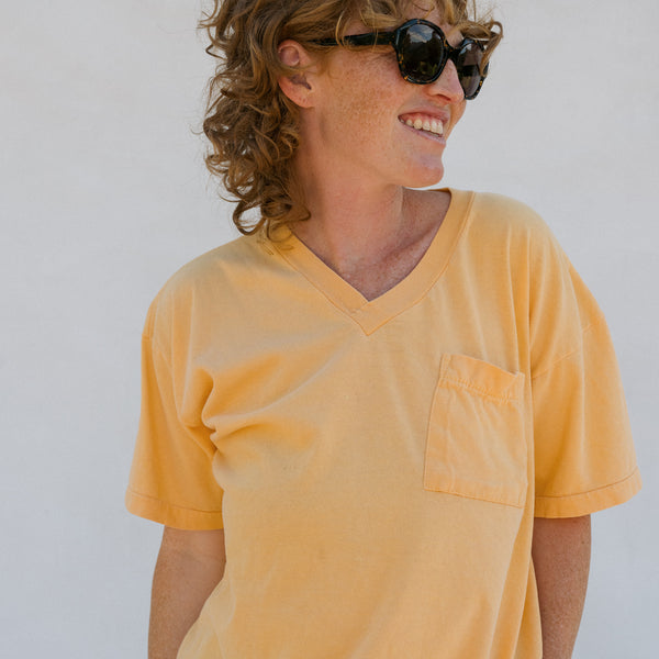 Man wearing a yellow t-shirt and sunglasses against a plain background