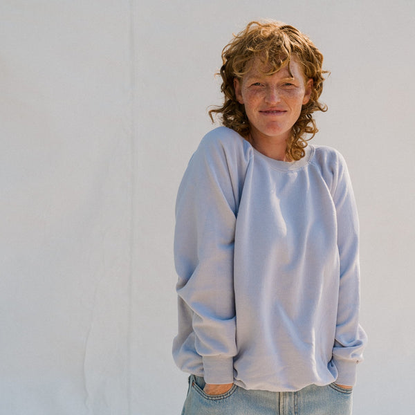Person wearing a light blue sweatshirt and jeans against a white background